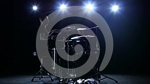 Drummer plays the melody on the drums energetically. Black background. Back light. Silhouette