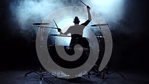Drummer plays the melody on the drums energetically. Black background. Silhouette. Slow motion