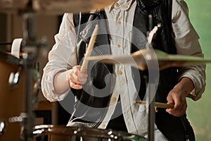 Drummer's rehearsing on drums before rock concert. Woman recording music on drumset in studio. Close up