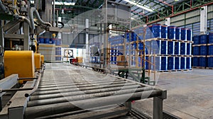 Drums holding 200 liters of chemicals are filled on a line. Inside the warehouse, stacks of blue barrel chemical barrels are