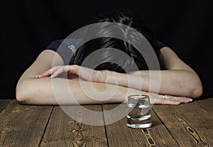 Drunk girl and alcohol on a wooden background, wedding rings on a table, divorce marriage