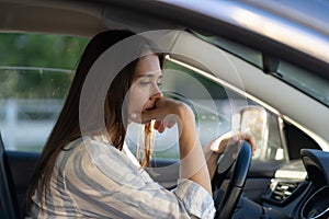 Drunk girl driving car. Unhappy tired young female in vehicle suffering from headache or handover