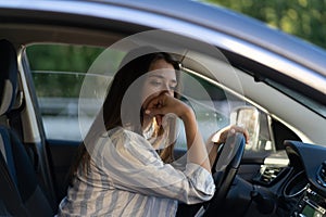 Drunk girl driving car. Unhappy tired young female in vehicle suffering from headache or handover