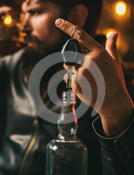 Drunk and hangover driver with car key in alcoholism problem and alcohol abuse concept. Man with beard holds glass of