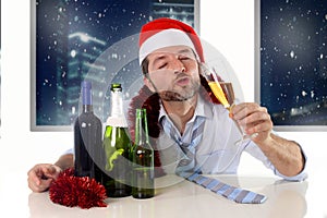 Drunk happy business man in Santa hat with alcohol bottles in new year toast with champagne glass
