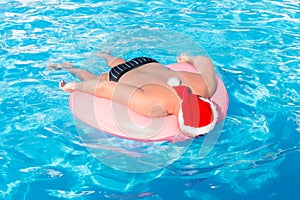 Drunk resting guy in santa claus hat on the inflatable circle in the swimming pool of the hotel photo