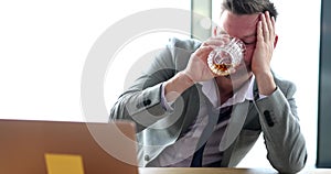 Drunk sad businessman holding glass with alcohol at workplace