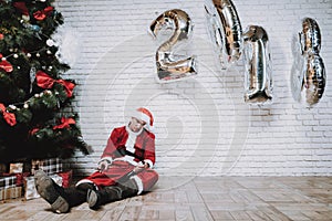 Drunk Santa Claus near New Year Tree after Party.