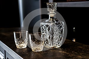 Drunk whiskey in crystal glasses. empty bottle and glasses for drinks on a dark wooden table. containers for alcoholic beverages