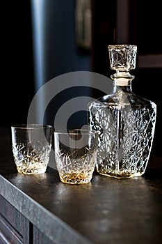 Drunk whiskey in crystal glasses. empty bottle and glasses for drinks on a dark wooden table. containers for alcoholic beverages