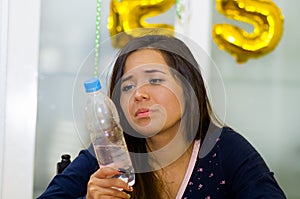 Drunk woman holding a plastic bottle of water, hangover concept