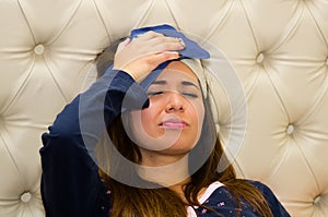 Drunk woman with a sleeping eye mak in her head and aplying a bag of ice in her head using her hand, hangover concept photo