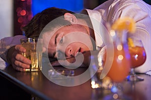 Drunk young man resting head on bar counter