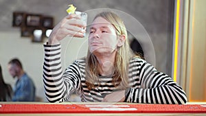 Drunken frustrated young man sitting at bar counter holding glass with drink and thinking. Portrait of depressed