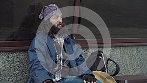 A drunken homeless man is sitting on the street.