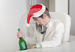 Drunken man in Christmas cap with bottle in a hand photo