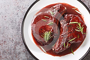 Drunken Pork Chops with red wine sauce and herbs closeup on the plate. Horizontal top view