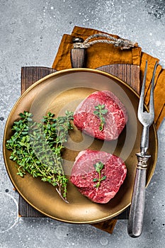 Dry aged Fillet Mignon Beef steak with herbs, raw marble meat. Gray background. Top view