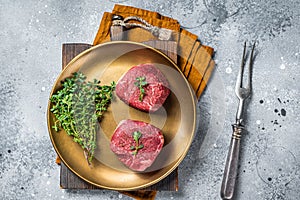 Dry aged Fillet Mignon Beef steak with herbs, raw marble meat. Gray background. Top view
