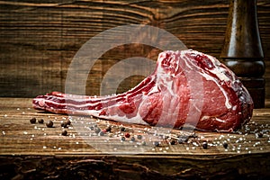 Dry aged raw tomahawk beef steak with ingredients for grilling