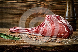 Dry aged raw tomahawk beef steak with ingredients for grilling