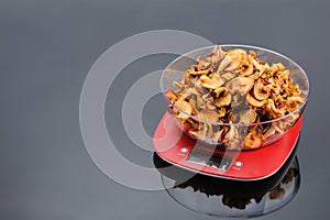 Dry apples in bowl on an electronic scale on grey mirror background with copy space