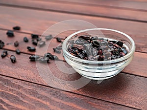 Dry barberries in a bowl on the background of dark wooden boards