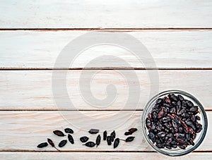 Dry barberries in a bowl on the background of white wooden boards