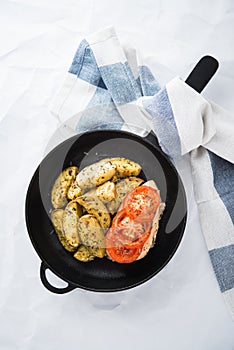 Dry basil parmesan fries and tomato chicken oven baked in cast-iron pan top view