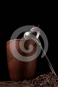 dry black chinese tea set,with strainer closeup,cups and teapot on background over old wood board