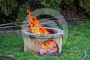 Dry branches burn in isolated campfire pit in the garden. High bright flames flickering on open garden fire pit