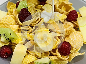 Dry breakfast cereal with fruits, a stream of milk.