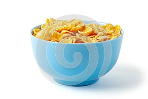 Dry breakfast cornflakes. Blue plate full of cereal. Isolated on white background.