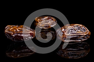 Dry brown date fruit isolated on black glass