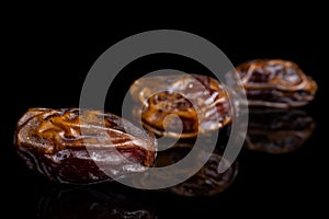 Dry brown date fruit isolated on black glass