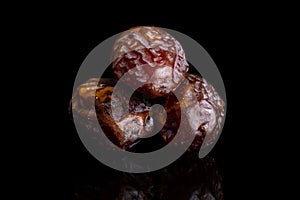 Dry brown date fruit isolated on black glass