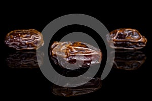 Dry brown date fruit isolated on black glass