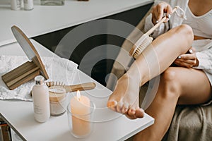 Dry brushing body brush for exfoliating dry skin, lymphatic drainage and cellulite treatment. Woman brushing skin leg photo