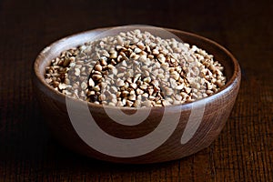 Dry buckwheat in brown wooden bowl.