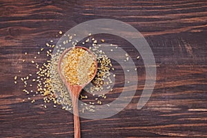 Dry bulgur grain in a wooden spoon.