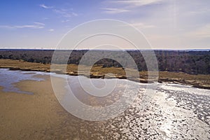 Dry bush land by the beach with clear sky copy space. Landscape of the mudflat with calm water surface reflection on a photo