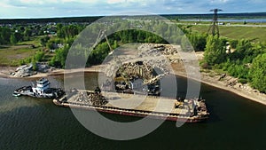 Dry cargo ship bulk carrier crane load crushed stones rock in river dock aerial view fly right