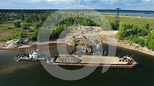 Dry cargo ship bulk carrier crane load crushed stones rock in river dock aerial view fly right