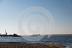 A dry cargo ship with open bilges is anchored in the middle of a wide river. A five-cargo ship in the outer waters of the Nikolaev