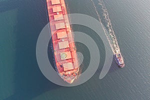The dry cargo vessel enters the port with the help of tugs. Photo from a helicopter. Bird's-eye view.