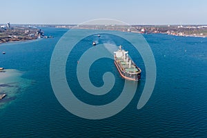 The dry cargo vessel enters the port with the help of tugs. Photo from a helicopter. Bird's-eye view