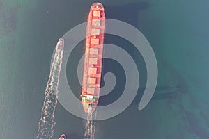 The dry cargo vessel enters the port with the help of tugs. Photo from a helicopter. Bird's-eye view