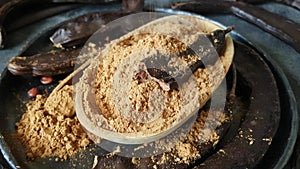 Dry carob pods and powder close up