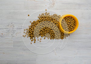 Dry cat or dog food in bowl on wooden background with empty copy space, top angle view. Pet food on gray wood surface. Pet care