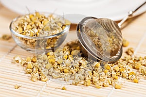 Dry chamomile with tea strainer and glass dish